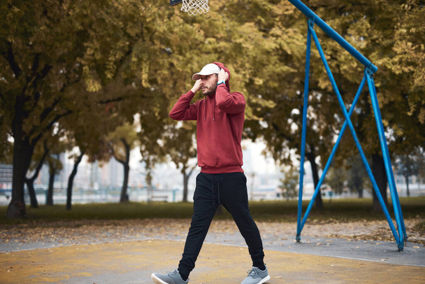 Athletic sporty man training in hoodie sweatshirt in urban city park / basketball court. - Photo, image