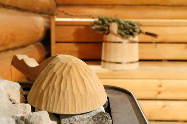 A concha de madeira está no aquecedor no fundo dos acessórios da sauna. Concentre-se na concha. - Foto, Imagem