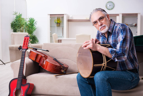 Reparador sênior do sexo masculino reparando instrumentos musicais em casa - Foto, Imagem