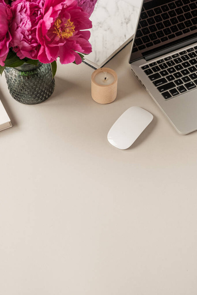 Laptop, mooie roze pioenroos tulp bloemen boeket op neutrale tafel achtergrond. Minimale kantoorruimte thuis. - Foto, afbeelding
