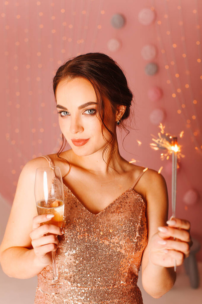 Tyttö mekko poseeraa vaaleanpunainen tausta kanssa sparklers ja lasi - Valokuva, kuva