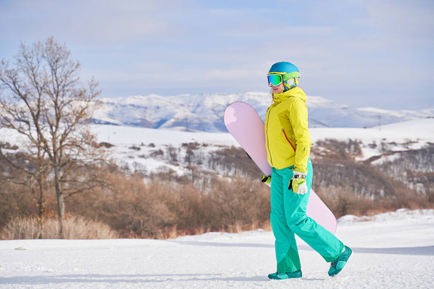 山を背景にスノーボードをする女 - 写真・画像