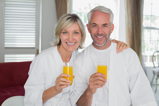 Happy mature couple holding orange juices - Zdjęcie, obraz