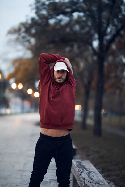 Athletic sporty man training in hoodie sweatshirt in urban city park. - Foto, Imagen