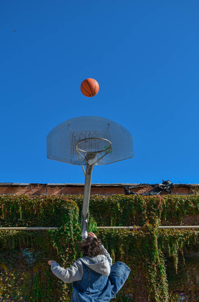 バスケットに向かってジャンプバスケットボールをしている若い男. - 写真・画像