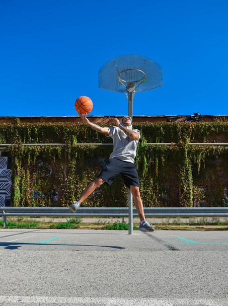 Татуйований чоловік грає в баскетбол у міському парку
. - Фото, зображення
