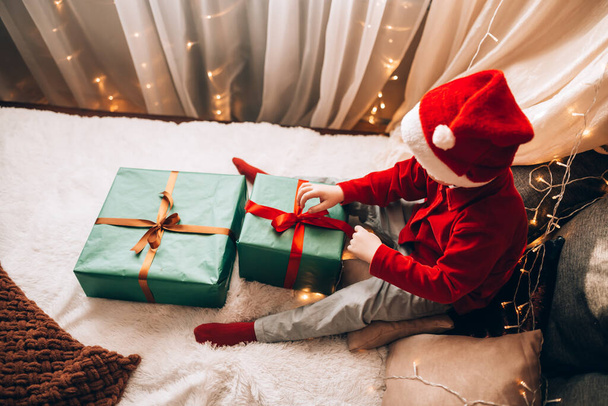 A boy holding a large box in a green package and a bow with a gift. Christmas mood - Foto, immagini