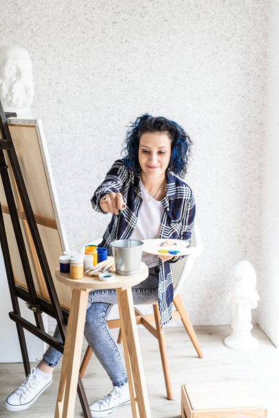 Creatieve vrouw kunstenaar schilderen van een beeld werken in haar atelier - Foto, afbeelding
