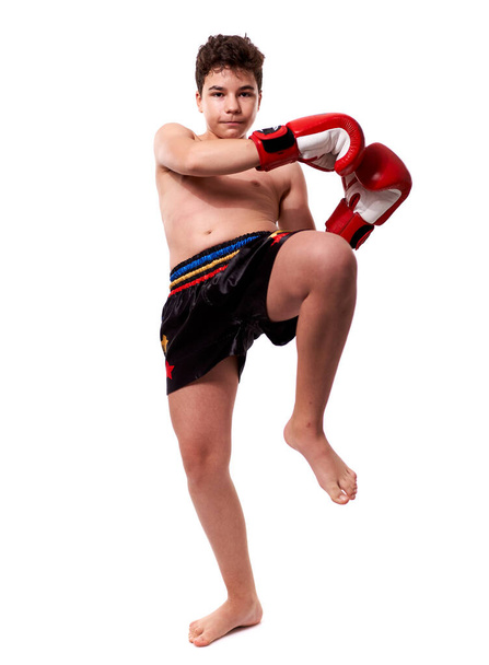 Young kickboxing fighter in red gloves with various strikes posing on white background - Фото, изображение