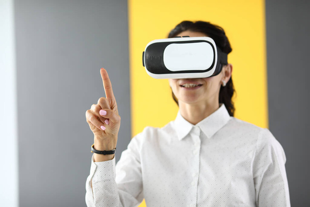 Woman in virtual reality glasses stands and holds her thumbs up. - Foto, Imagem