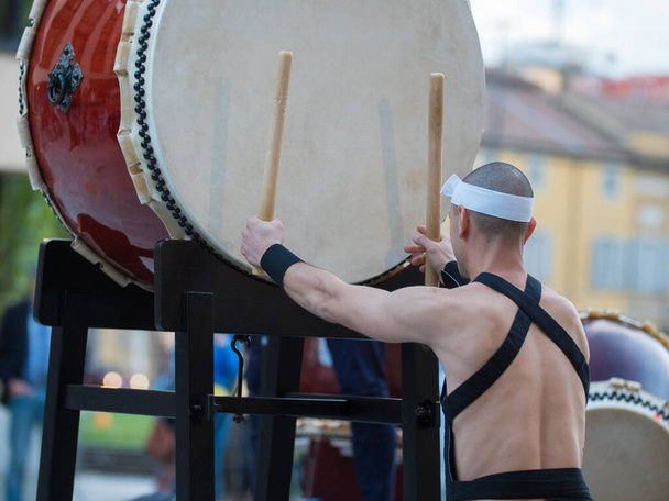 Man with Headband Gra na wertykalnej perkusji japońskiej tradycji muzycznej podczas imprezy plenerowej. - Zdjęcie, obraz