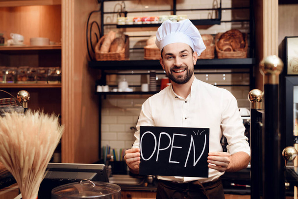 Young Happy Man with Open Sign Standing in Bakery. - Foto, imagen