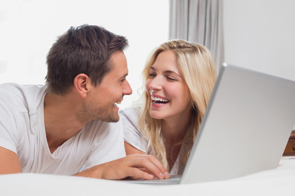 Cheerful relaxed casual couple using laptop in bed - Zdjęcie, obraz