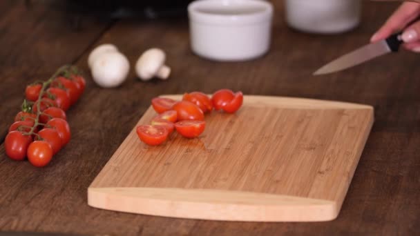 Женские руки режут вишневые помидоры наполовину ножом. - Кадры, видео