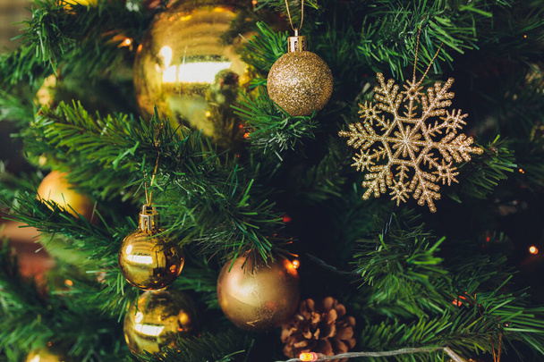 Closeup of christmas fir tree decorated with gold, toys, balls and garland. Traditional winter holidays Christmas New Year. - Photo, image