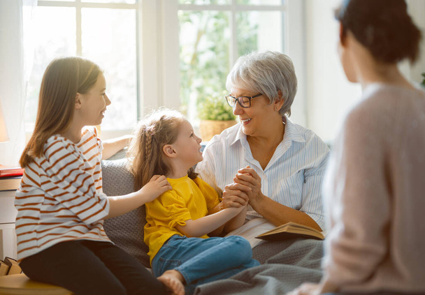 A nice girls, their mother and grandmother enjoying spending time together at home.  - Foto, imagen