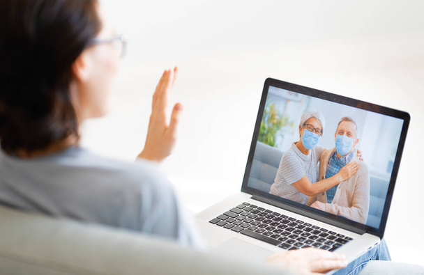 Woman is using pc for remote talking with parents during coronavirus and flu outbreak. Virus and illness protection, home quarantine. COVID-2019. - Valokuva, kuva