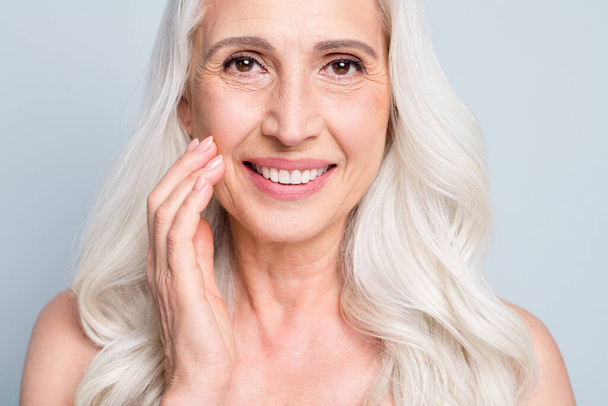 Close up photo of beautiful aged woman grey hair lady applying daily night cream cheek isolated grey color background - Foto, Imagem