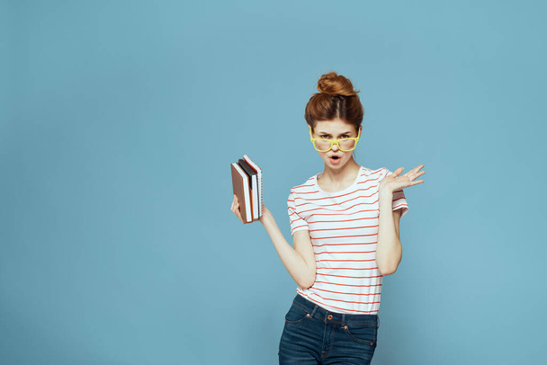 Ženské studentky s knihami v rukou na modrém pozadí a žluté brýle model účes oříznutý pohled - Fotografie, Obrázek