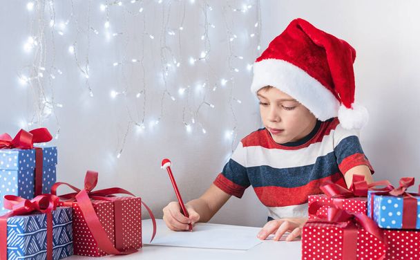  Child in a Santa hat writes a letter to Santa. - Foto, afbeelding