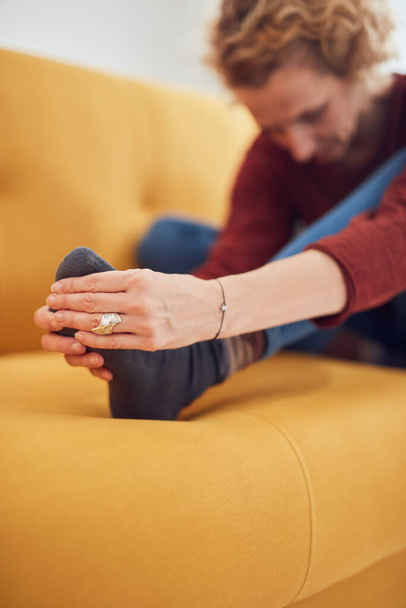 Mujer con pies dolor intenso sentada en un sofá en casa. - Foto, Imagen