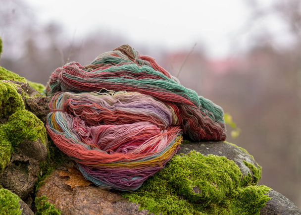 stones overgrown with green moss, colored wool yarn skeins, handicraft concept, hand knitting, autumn time, handicrafts at home - Photo, Image