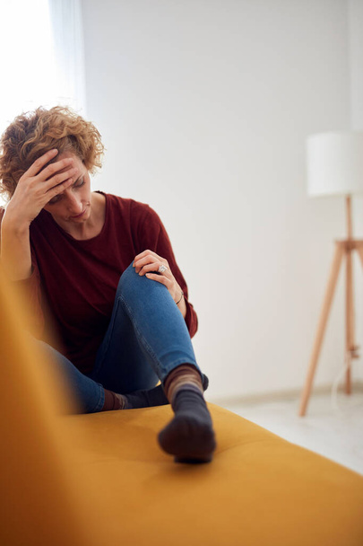 Жінка з коліном і проблемою головного болю сидить на дивані вдома
. - Фото, зображення
