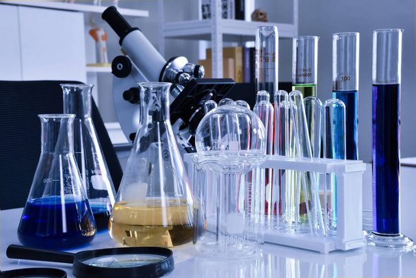 Une loupe et un ensemble de verrerie de laboratoire de chimie sont placés sur une table en acier inoxydable. - Photo, image