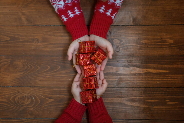 Vele kleine geschenken in twee kinderen handen op donkere houten achtergrond - Foto, afbeelding