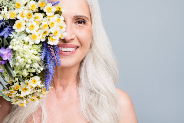 Closeup photo of beautiful retired woman hide half face big bunch wild flowers coquettish isolated grey color background - Photo, image