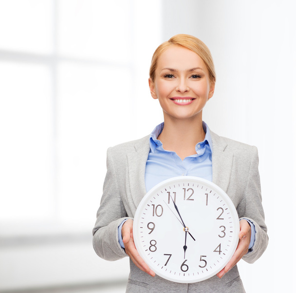 Smiling businesswoman with wall clock - Фото, изображение