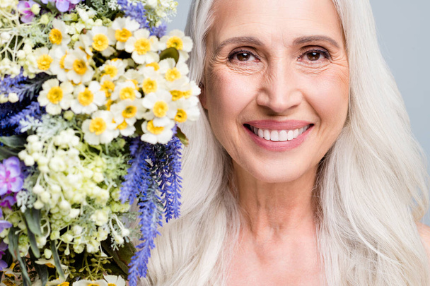 Close up photo of beautiful retired woman enjoy smell big bunch wild flowers toothy smiling isolated grey color background - Foto, immagini