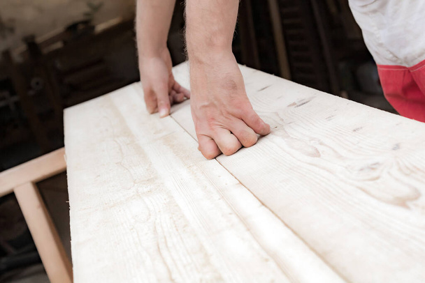 Férfi asztalos, aki fából készült anyaggal dolgozik garázsban. - Fotó, kép