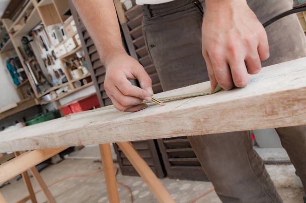 Male carpenter working with wood material in a garage. - Φωτογραφία, εικόνα