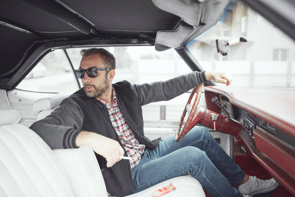 Férfi retro ruhák kezében cigaretta és vezetés vintage amerikai autó. - Fotó, kép