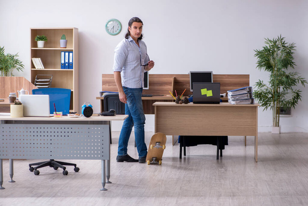 Young male employee with skateboard in the office - Photo, image