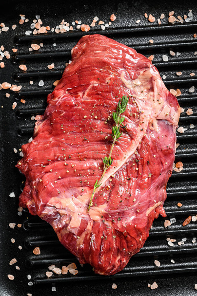 Rauwe gemarmerde biefstuk op een grillpan. Zwarte achtergrond. Bovenaanzicht. - Foto, afbeelding