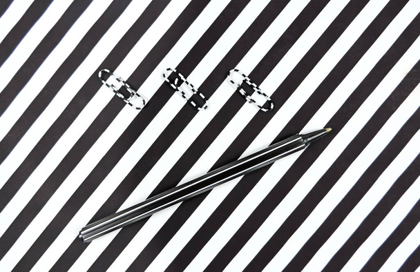 striped pen on a striped background, black and white stripes, copy space, minimalism, contemporary style - Photo, Image