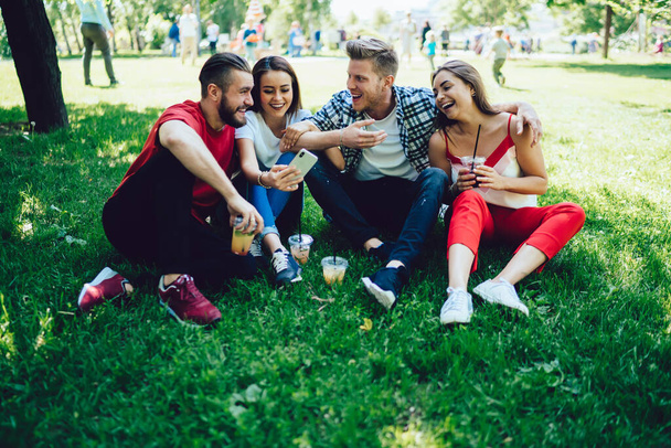 Group of joyful male and female vloggers shotting selfie video for communicate with social followers during weekend in public park,happy hipster guys reading funny news on website during double date - Foto, Bild