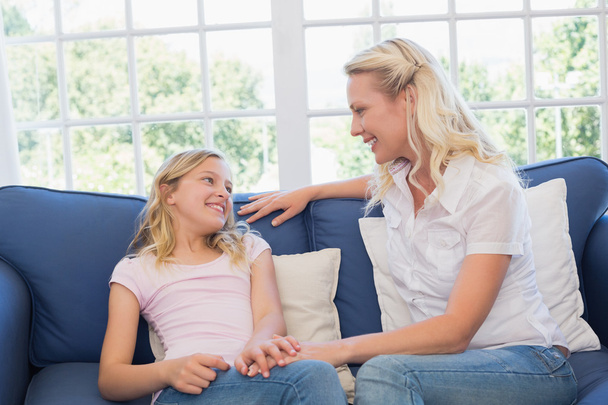 Mother and daughter sitting on sofa at home - Foto, imagen