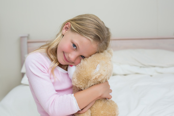 Young girl embracing stuffed toy in bed - 写真・画像
