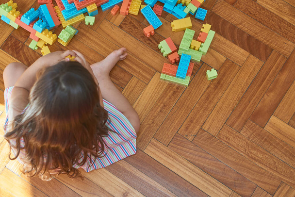 Mädchen spielt mit Klötzen auf dem Holzboden in ihrem Zimmer - Foto, Bild