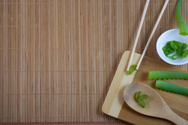 Flatley aloë Vera bladeren en stukken medische plant op een bamboe servet snijden Board lepel gemaakt van milieuvriendelijke materialen witte plaat - Foto, afbeelding