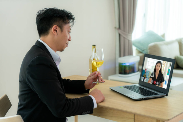 Asiático hombre virtual happy hour reunión y beber vino de uva blanca en línea junto con su amigo en videoconferencia con tableta digital para una reunión en línea en video cal - Foto, Imagen
