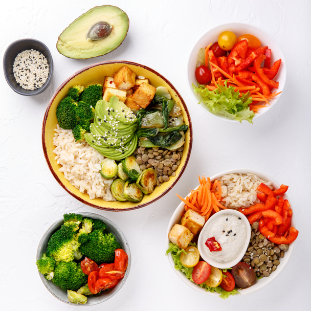 Buddha bowls on white background. Colorful bowls with vegetables, healthy grains, and protein. Healthy vegan food, vegetarian food concept. Top view.  - Photo, Image