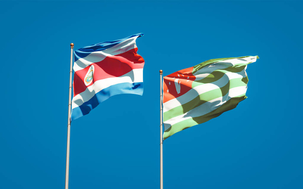 Krásné národní vlajky Abcházie a Kostariky společně na pozadí oblohy. Koncept 3D uměleckých děl. - Fotografie, Obrázek