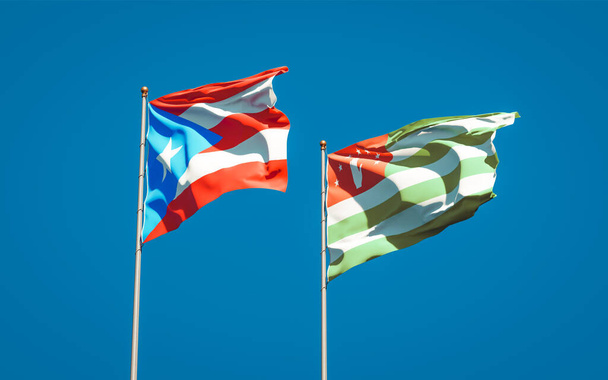 Krásné národní státní vlajky Puerto Rico a Abcházie společně na pozadí oblohy. Koncept 3D uměleckých děl. - Fotografie, Obrázek