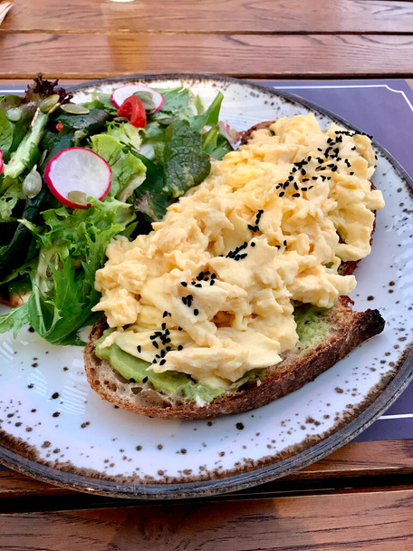 Scrambled Egg with Avocado Smash on Bread and Salad for Breakfast. Healthy Organic Food. - Zdjęcie, obraz