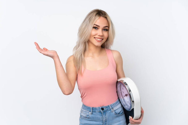 Teenager girl over isolated white background with weighing machine - Fotoğraf, Görsel