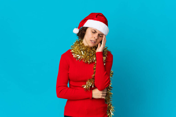 English girl with christmas hat isolated on blue background with headache - Foto, imagen